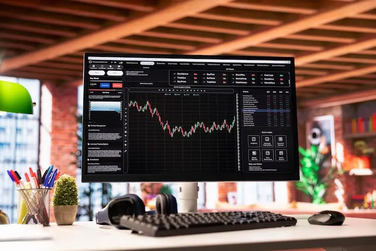 A computer monitor on a desk displaying a complex cryptocurrency trading interface with candlesticks and data charts