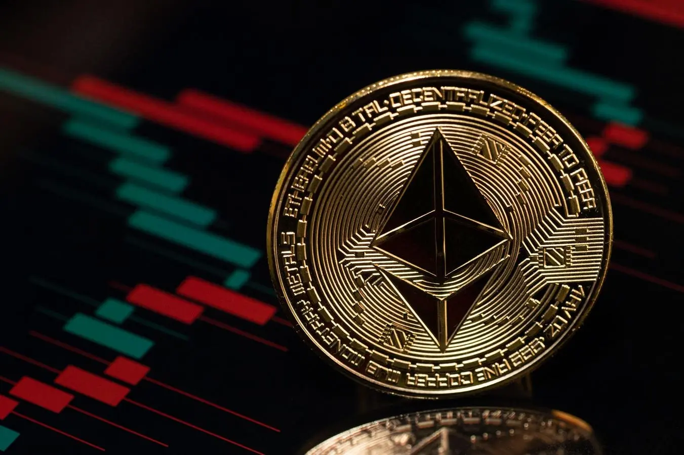 Close-up of a gold Ethereum coin featuring the octahedron logo against a blurred red and green trading chart