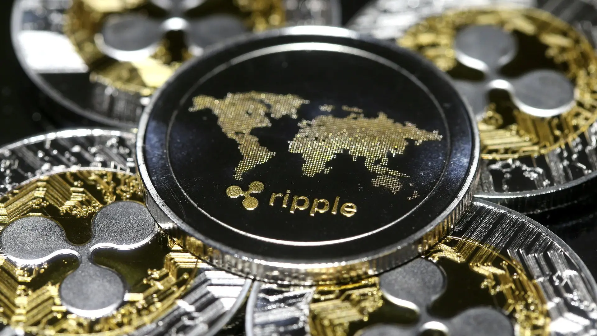 Close-up of gold and silver physical Ripple XRP coins featuring a world map and the Ripple logo