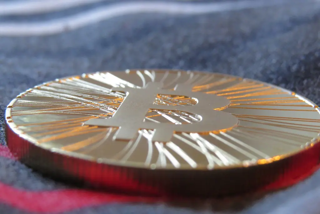 Close-up de uma moeda dourada física com o símbolo do Bitcoin.