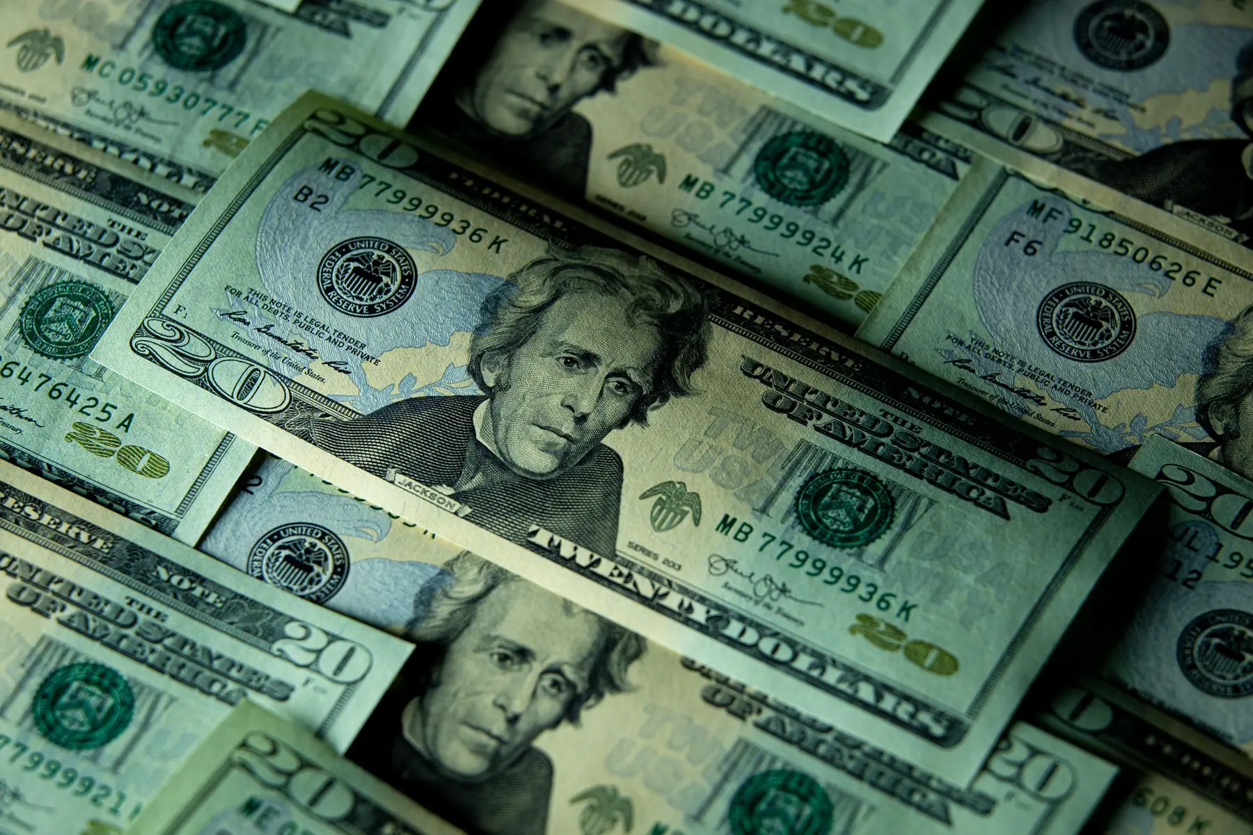 A close-up, high-angle shot of scattered twenty-dollar bills featuring Andrew Jackson.