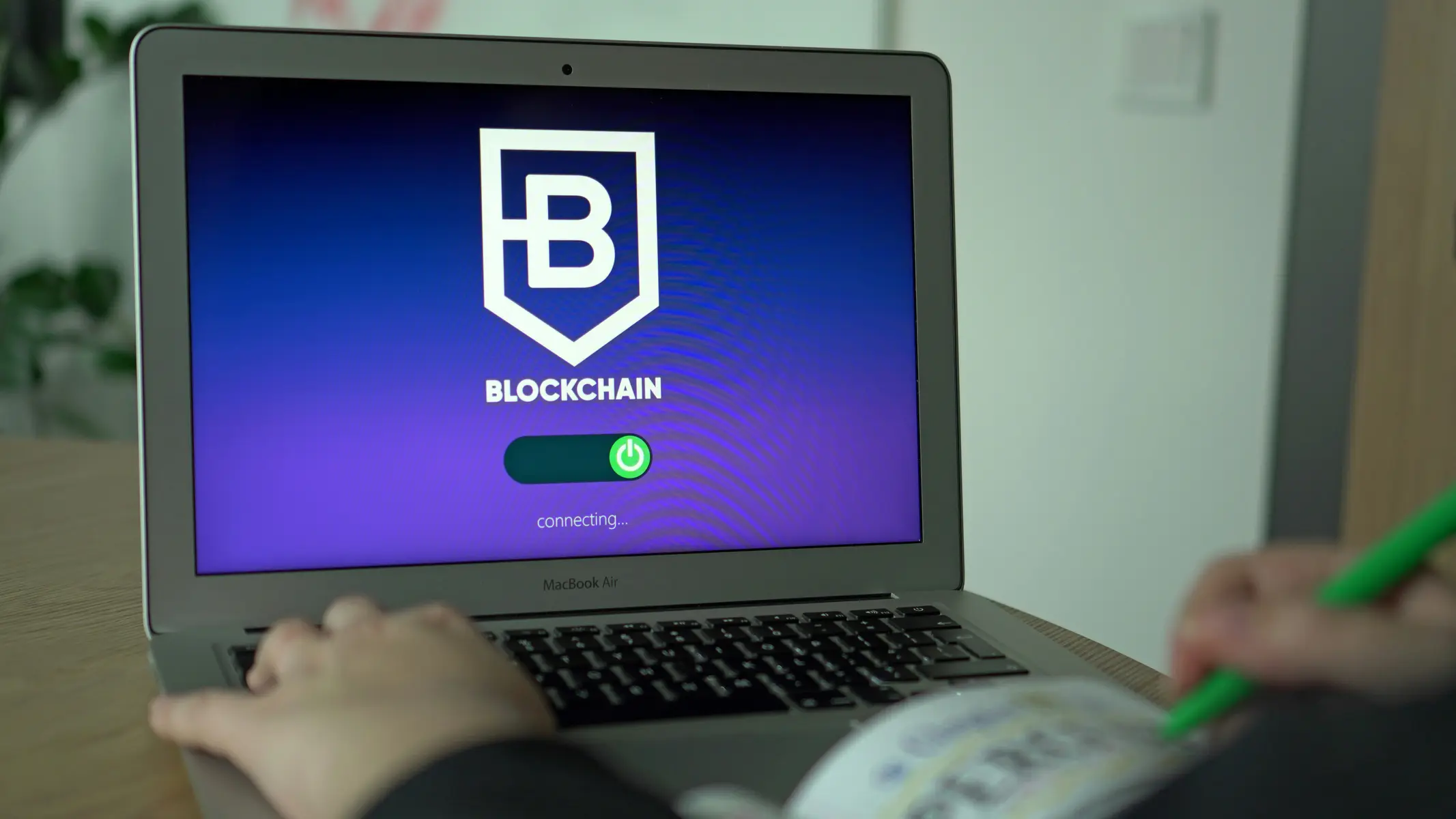 Pessoa utilizando um laptop que exibe o logotipo de blockchain na tela.
