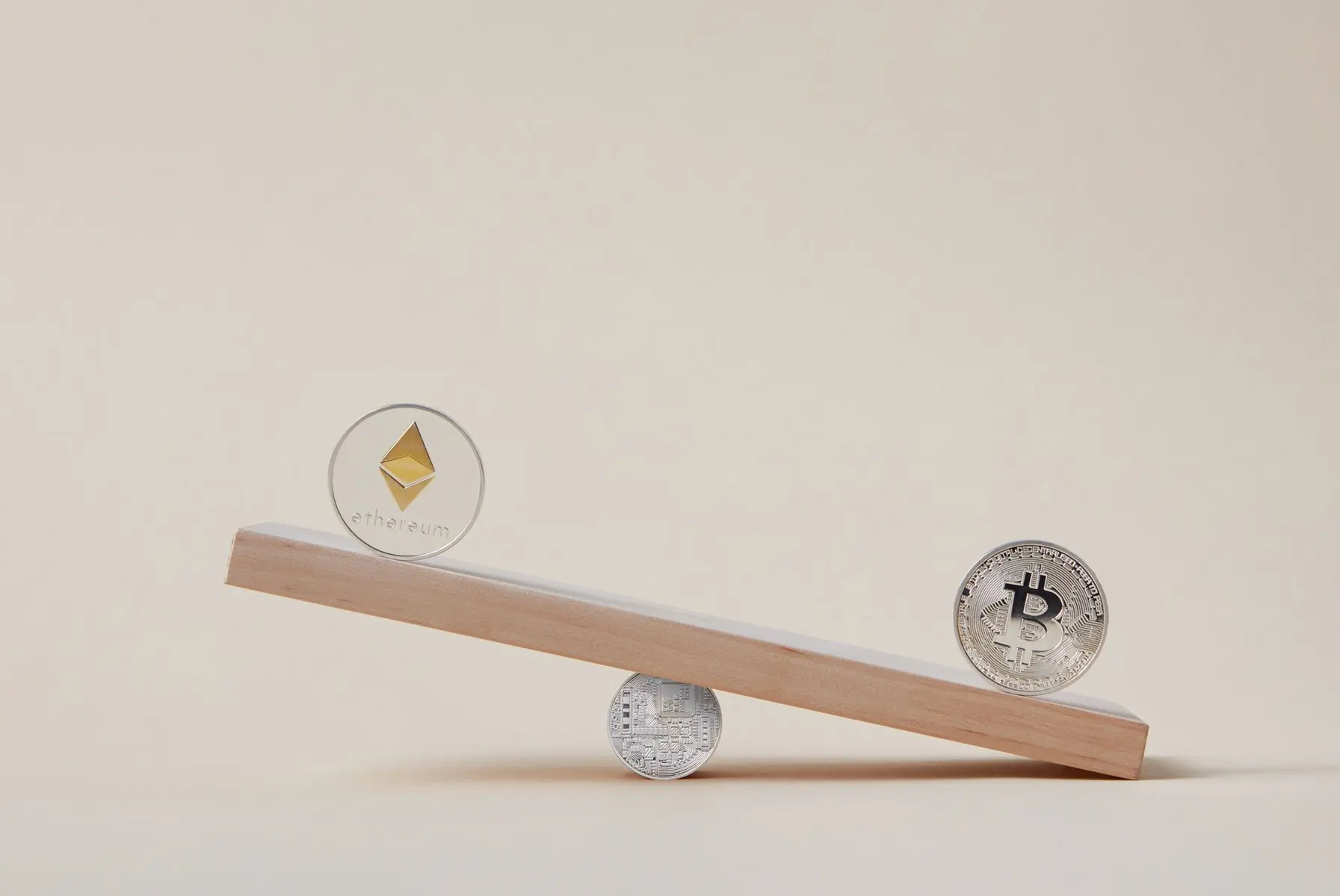 Ethereum and Bitcoin physical tokens balancing on a wooden plank over a Litecoin coin