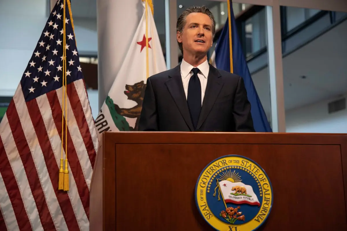 Gavin Newsom falando atrás de um pódio com o selo do Governador do Estado da Califórnia.